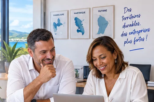 Deux consultants souriants devant un ordinateur, cartes de la Guadeloupe, de la Martinique et de la Guyane au mur